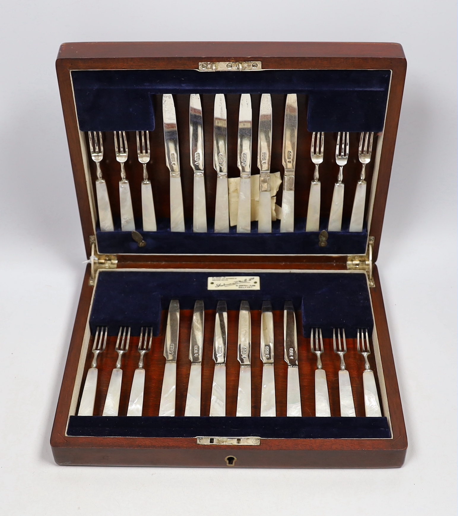 A cased set of twelve pairs of George V silver mother of pearl handled dessert knives and forks, Sheffield 1914, in Belfast Retailer's box